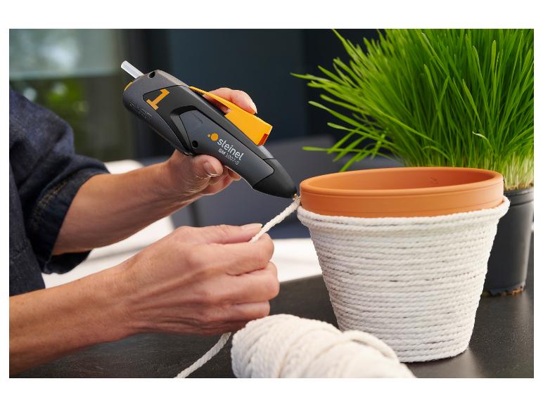 Femme utilisant un pistolet à colle chaude STEINEL pour décorer un pot de fleurs avec de la corde.