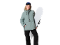 Femme en veste de ski verte et pantalon de ski noir avec snowboard et lunettes de ski.
