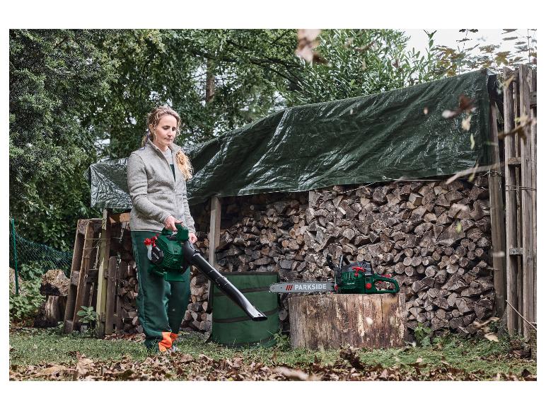 Femme utilisant un souffleur de feuilles, avec une tronçonneuse sur une souche en bois.