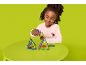 Fille jouant avec des ensembles de construction magnétiques colorés sur une table verte.