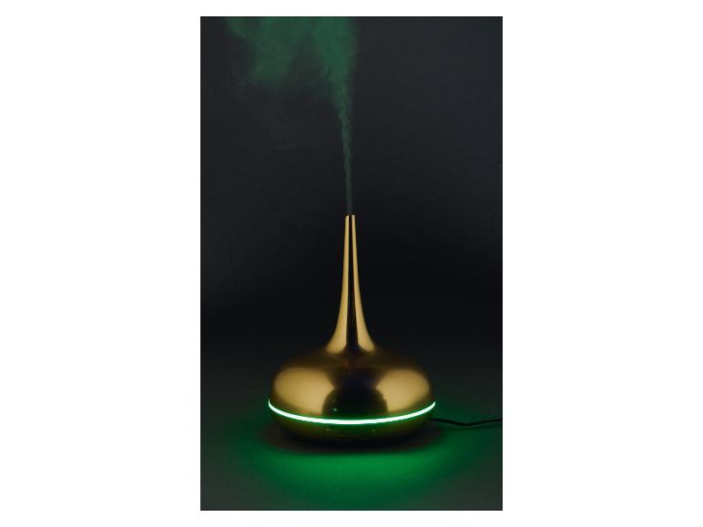 Diffuseur d'arômes doré avec lumière verte et fumée sur fond sombre
