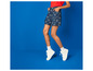 Un mannequin porte un short en jean avec un imprimé Levi's et des baskets blanches.