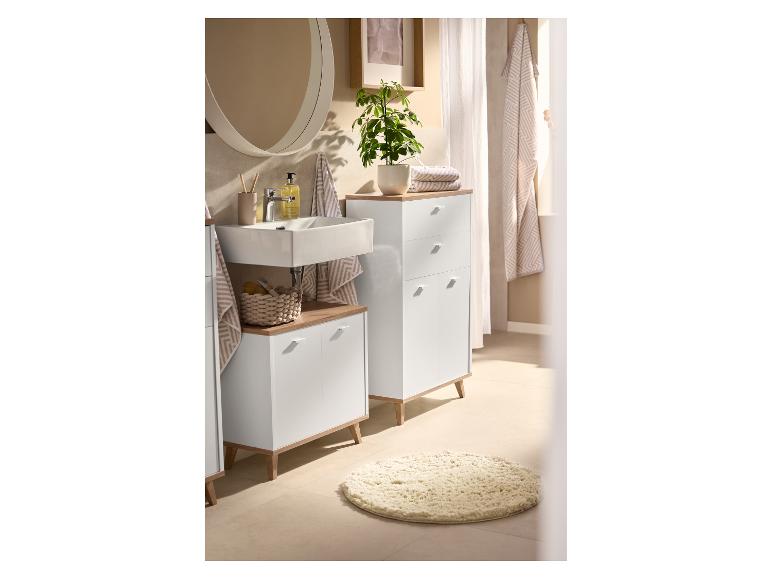 Salle de bain avec des armoires blanches, des comptoirs en bois, un lavabo et un miroir rond.