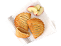 Trois chaussons aux pommes dorés et une pomme coupée sur un torchon blanc.
