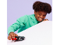 Enfant souriant en sweat à capuche vert jouant avec une voiture jouet noire et rouge.