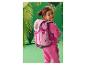 Fille souriante en survêtement rose avec un sac à dos rose à motifs de chien et de dinosaures.