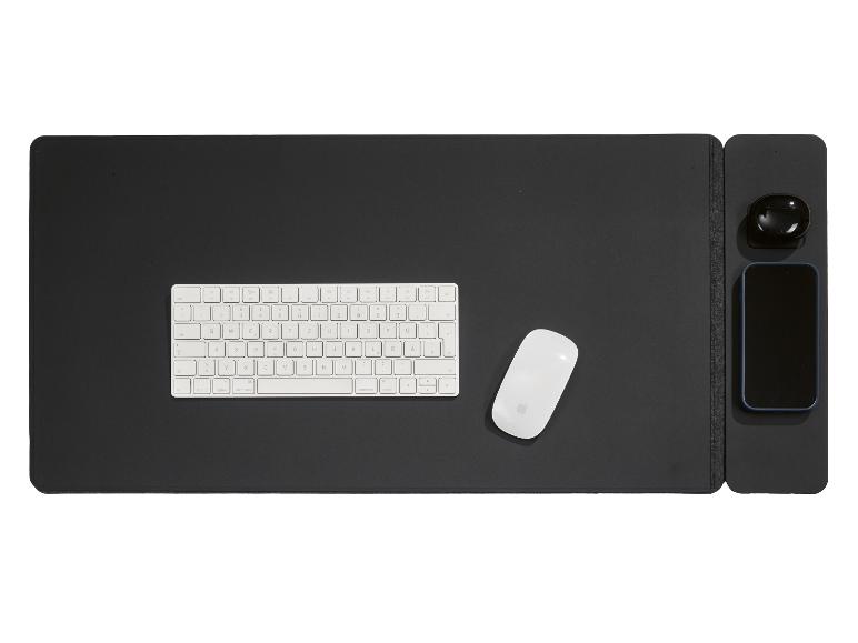 Clavier, souris, écouteurs et smartphone sur un tapis de bureau noir.