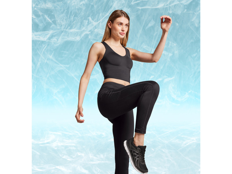 Femme en soutien-gorge de sport noir et leggings noirs avec des baskets noires.
