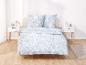 Un lit avec une couette bleu clair à imprimé floral blanc.