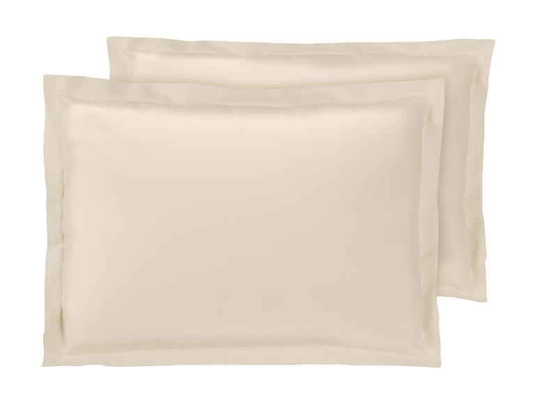 Deux taies d'oreiller beige clair au design simple et élégant.