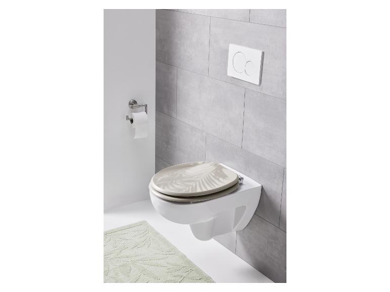 Des toilettes avec un abattant de toilette beige avec un motif de feuilles de palmier.