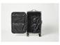 Valise grise ouverte avec intérieur noir et compartiments zippés.