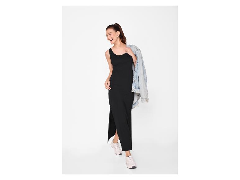 Femme en robe longue noire et veste en jean, souriante