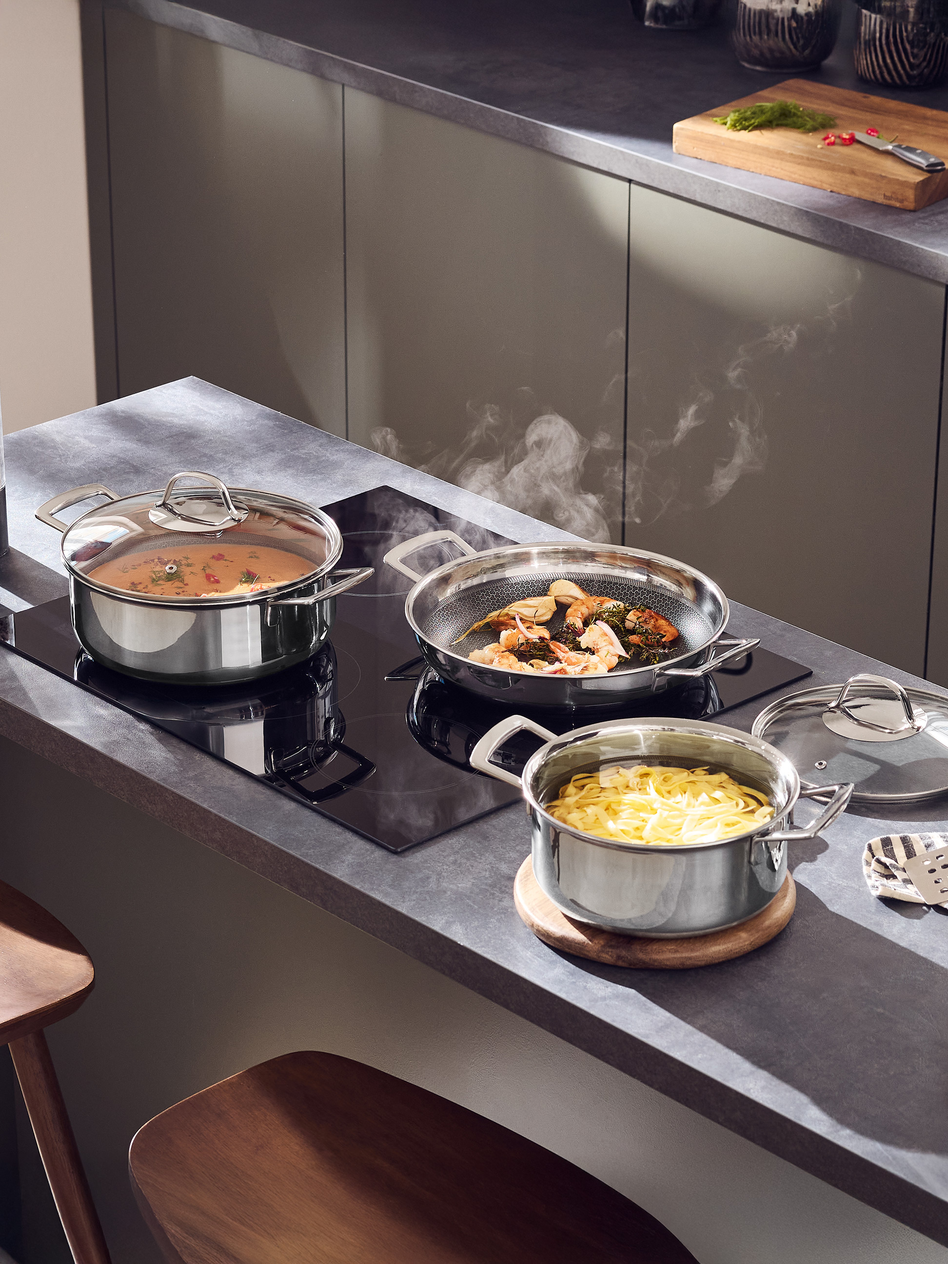 Casseroles et poêles en acier inoxydable avec de la nourriture qui cuit dans une cuisine moderne.