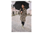 Femme portant un manteau léopard et des bottes assorties, marchant sous un parapluie noir.