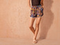Femme portant un short à fleurs et des sandales blanches.