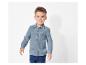 Un jeune garçon porte une chemise en gaze bleue et un jean.
