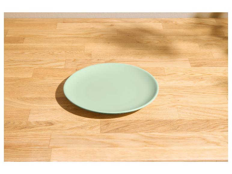 Assiette vert clair sur une table en bois clair avec des ombres