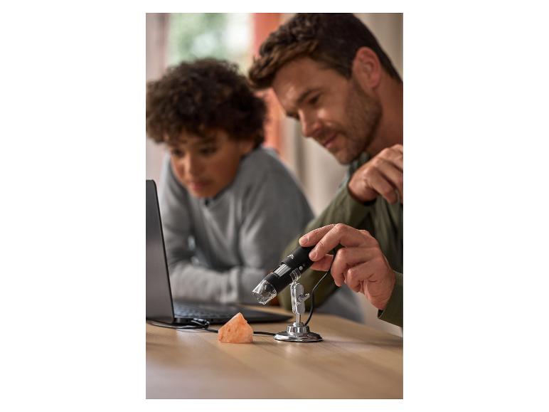 Père et fils utilisent un microscope numérique pour examiner une roche rose.