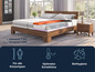 Un lit en bois avec un matelas multicouche et une table de chevet.