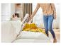 Une personne nettoie un canapé avec un aspirateur Dyson sans fil.