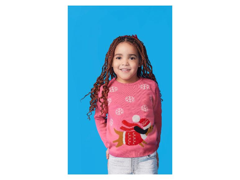 Fille souriante dans un pull rose avec un chien de Noël
