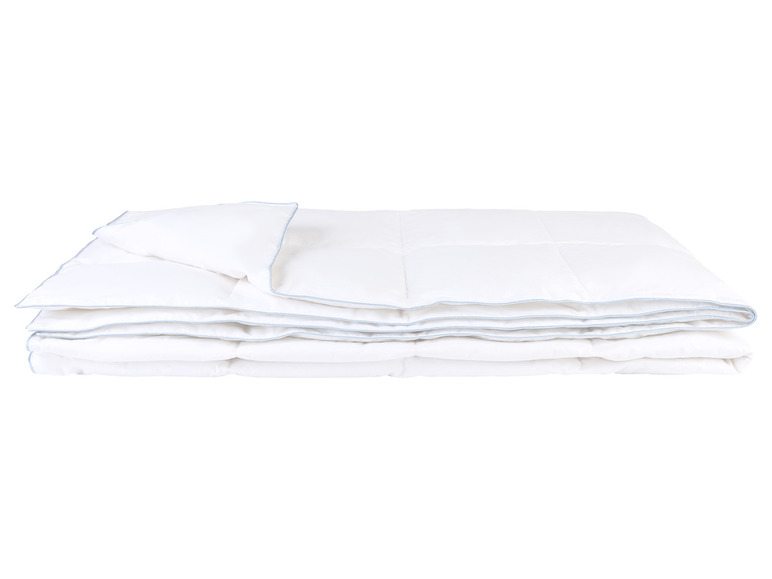 Une couette et un oreiller blancs, pliés et prêts à l'emploi.