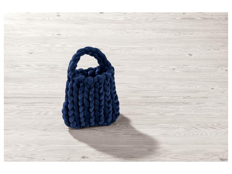 Sac à main en tricot bleu marine sur fond bois.