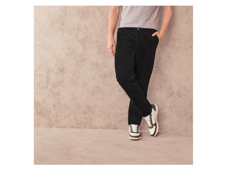 Pantalon en velours côtelé noir et baskets blanches avec des accents verts.