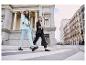 Deux femmes élégantes traversent un passage piétonnier en costumes clairs.