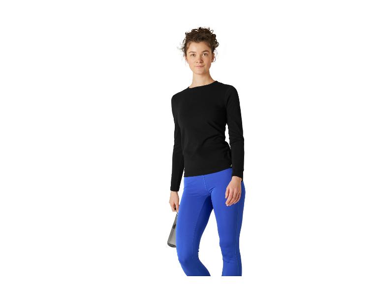Femme en haut noir à manches longues et legging bleu, tenant une bouteille d'eau.
