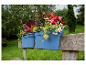 Jardinières bleues avec des fleurs colorées et vibrantes dans un jardin verdoyant.