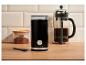 Moulin à café électrique noir, cafetière à piston et pot de café moulu sur un comptoir en bois.