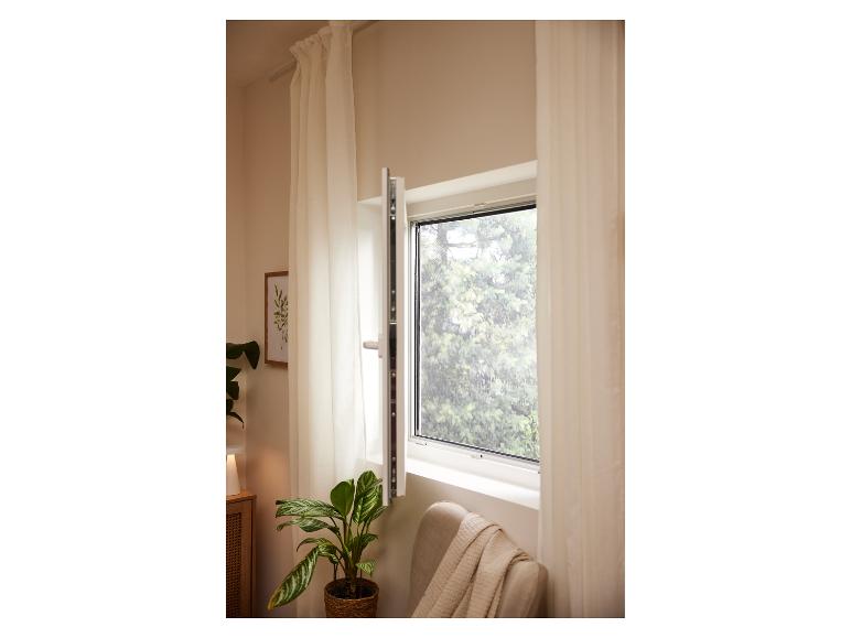 Fenêtre ouverte avec moustiquaire, rideaux, plante en pot et fauteuil avec couverture.