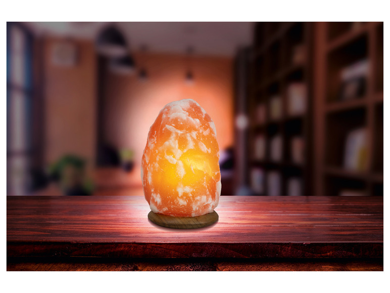 Une lampe en sel rose sur une table en bois.