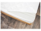 Un matelas blanc avec un cadre en bois sur un sol en bois.