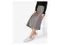Une femme porte une jupe en satin gris et des baskets blanches.