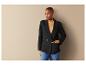 Une femme portant un blazer noir et un pull beige.