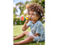 Un enfant souffle des bulles avec un souffleur à bulles coloré sur l'herbe.