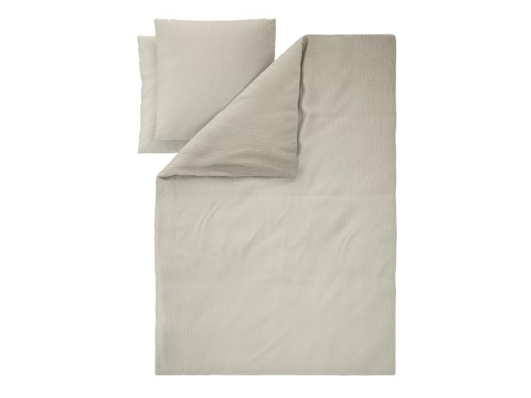 Parure de lit beige clair avec deux oreillers, présentant un motif texturé subtil.