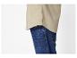 Gros plan d'une personne portant une chemise beige et un jean bleu.