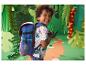Enfant souriant avec un sac à dos bleu dans un décor de jungle en papier.