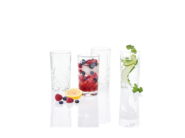 Quatre verres avec différentes boissons, dont un avec des framboises et des myrtilles.