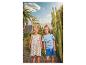 Fille en robe citron et garçon en t-shirt dinosaure et short bleu en extérieur.