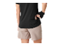 Femme en haut de sport noir et short beige, mettant une barre de céréales dans la poche arrière.