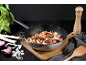 Wok avec nouilles, viande et légumes, entouré d'ingrédients frais.