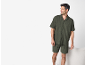 Homme en chemise à manches courtes vert foncé et short assorti, souriant et regardant à droite.