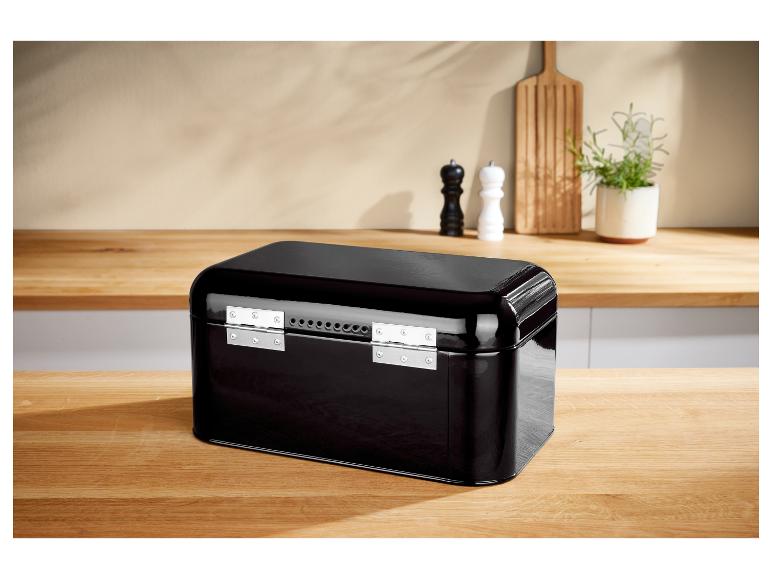 Boîte à pain en métal noir sur une table en bois dans une cuisine.