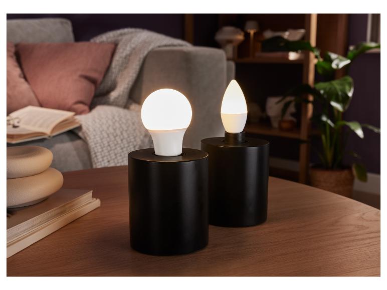 Deux lampes noires avec des ampoules LED rondes et en forme de goutte sur une table en bois.