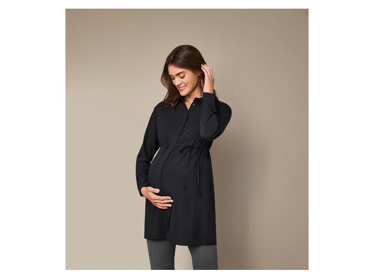 Femme enceinte portant une chemise noire et un pantalon gris.